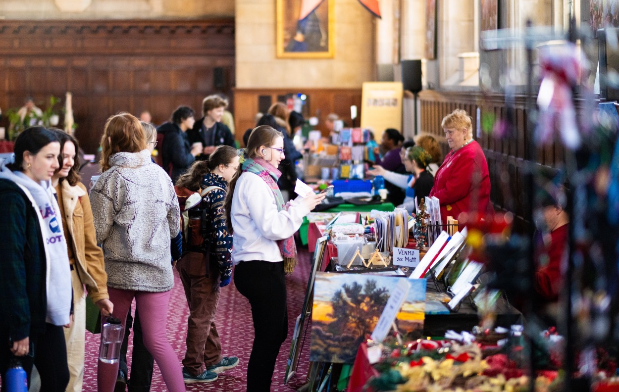 People interacting with holiday vendors in Great Hall