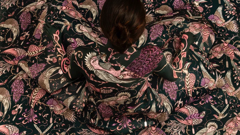 Cecilia Paredes photographed from above, sitting amidst skirt that fills background with pattern of flora and fauna.