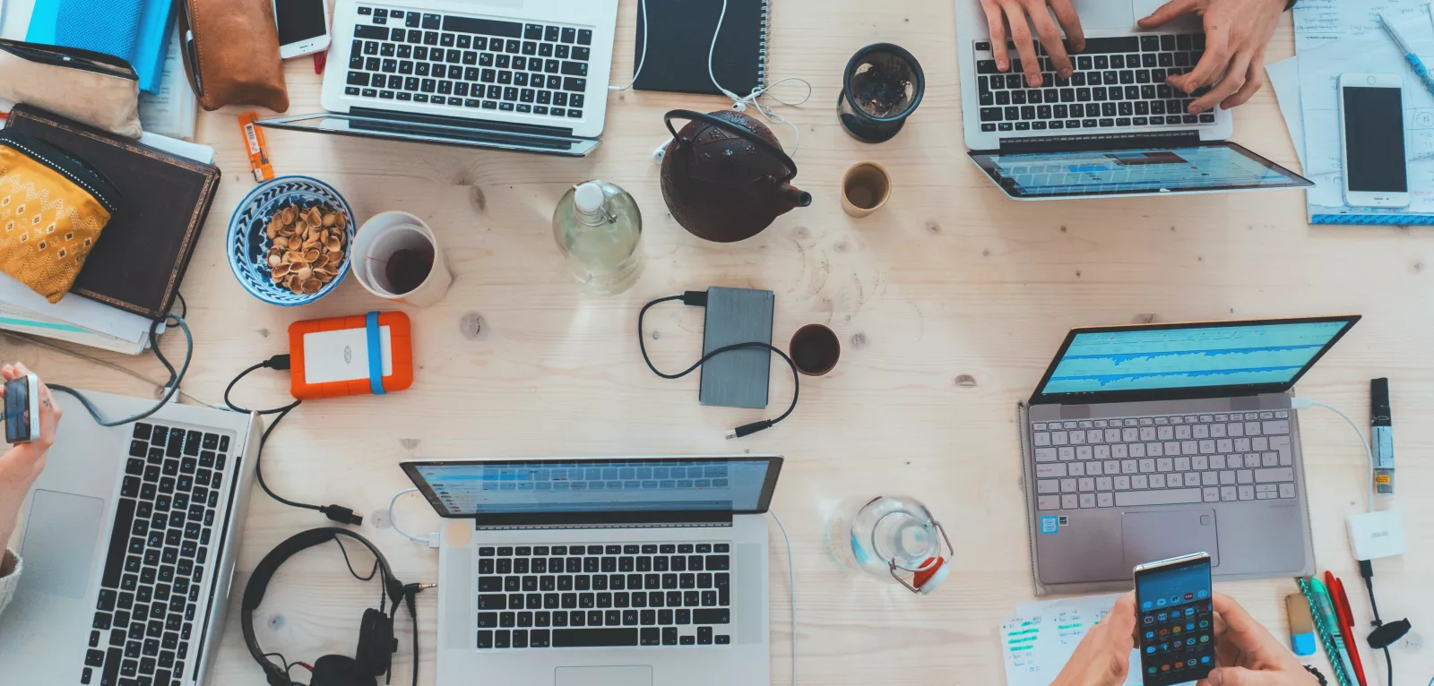 People sitting around a table top with different electronic, hearing and writing tools on it. 