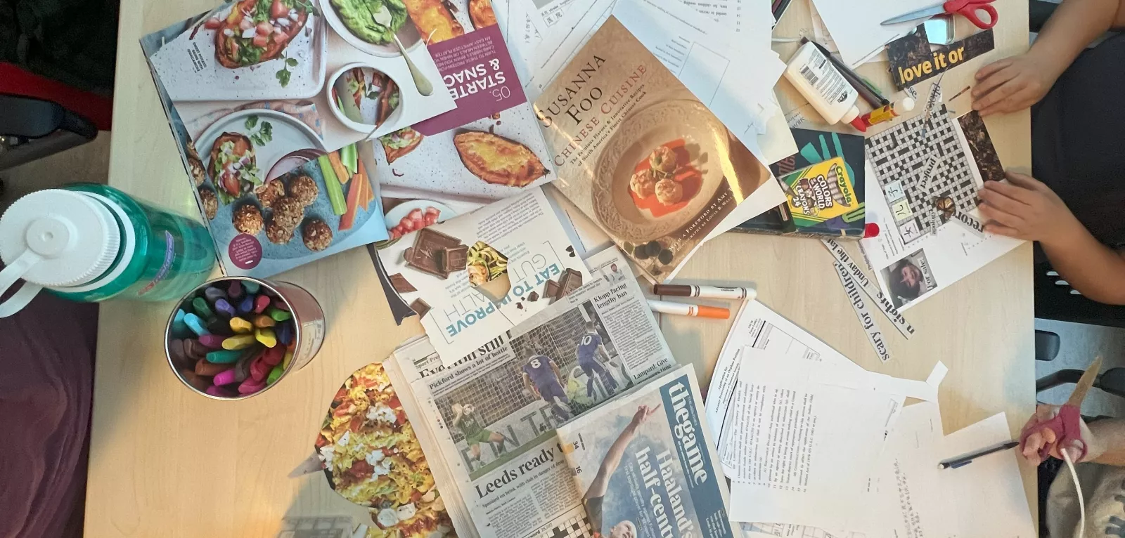 Table full of collage materials (magazine cutouts, pens, glue, etc.)