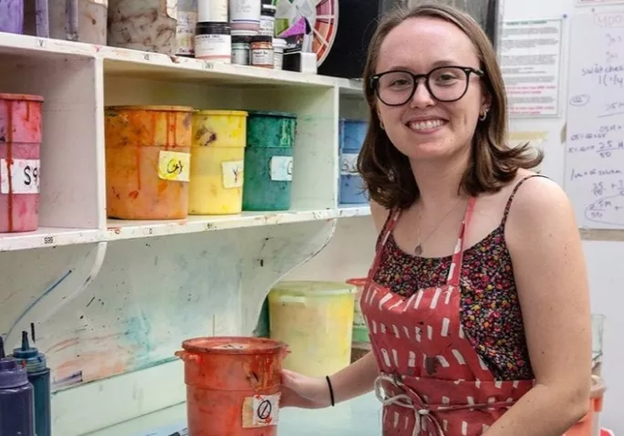 Francis Miller posing in front of paints at the Fabric Workshop and Museum in Philadelphia