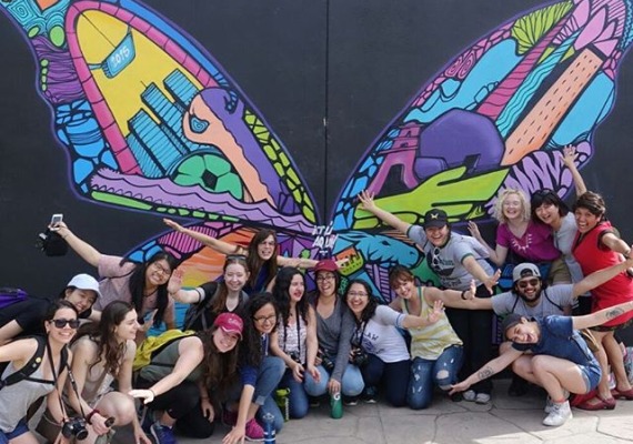 360 students gather in front of a butterfly mural with arms outstretched