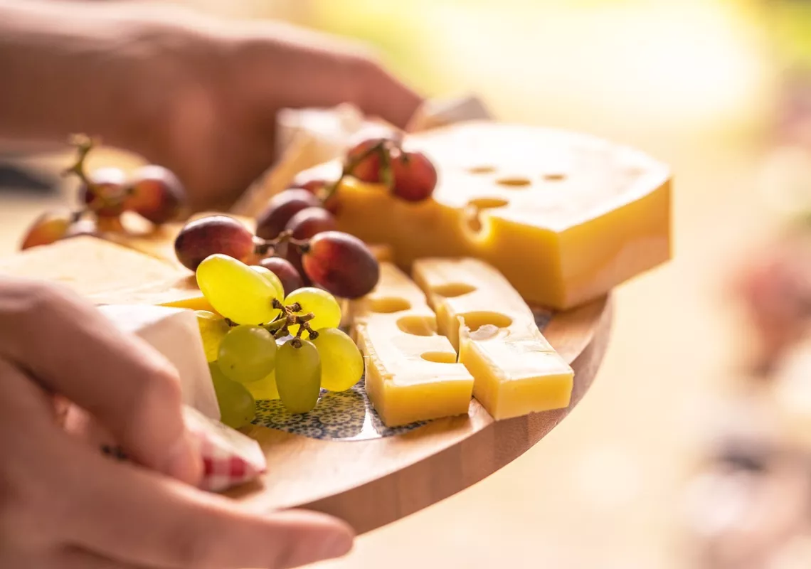 Hands holding a plate with cheese and grapes