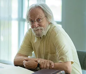 Bill Dunham seated at a table behind several open books.