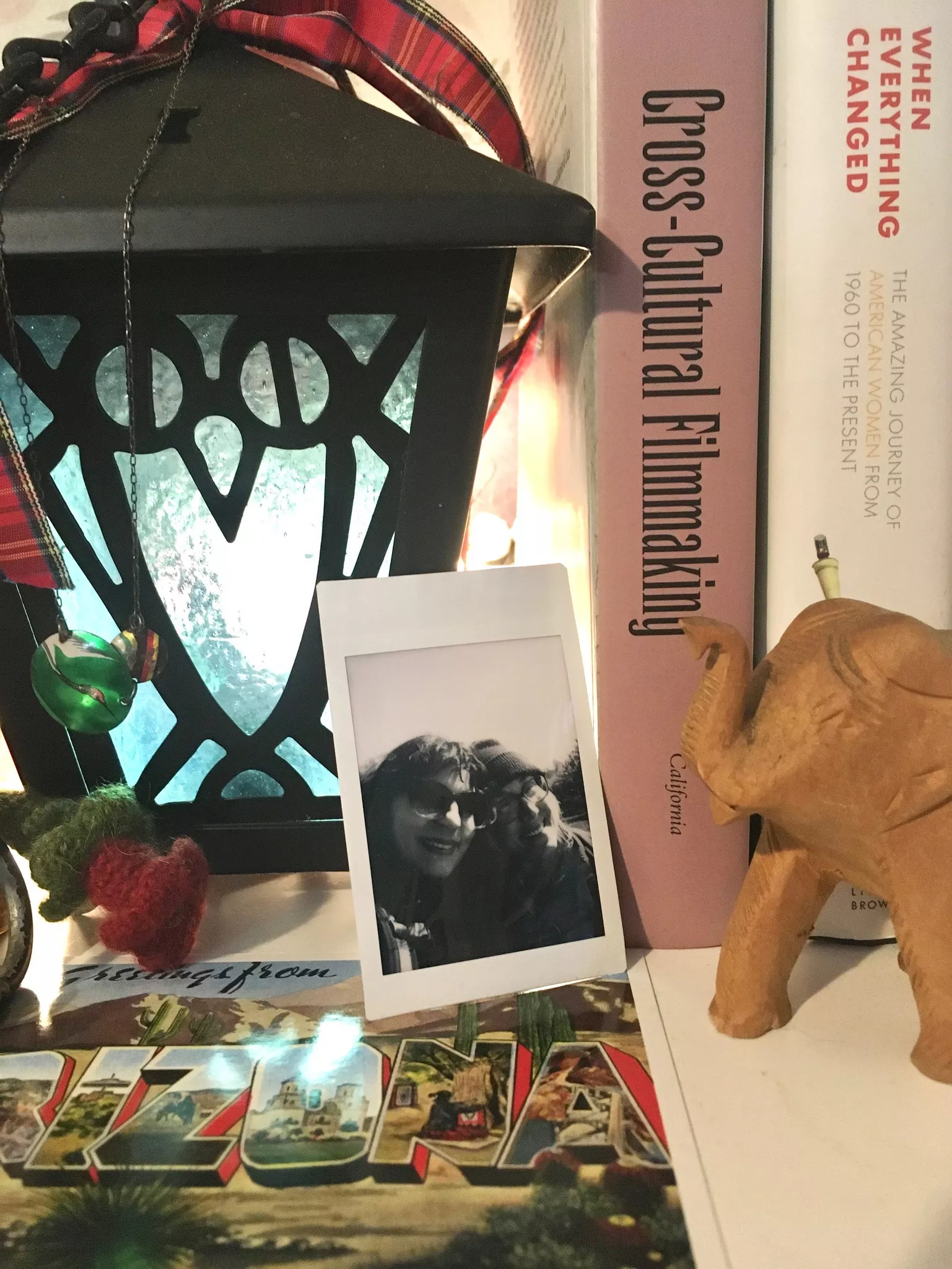 Bookshelf featuring a blue Bryn Mawr College lantern and a polaroid of Schenck and Sclafani