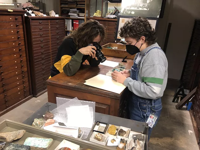 Artist and student look at empty boxes that remain from the uranium once stored in the collection.