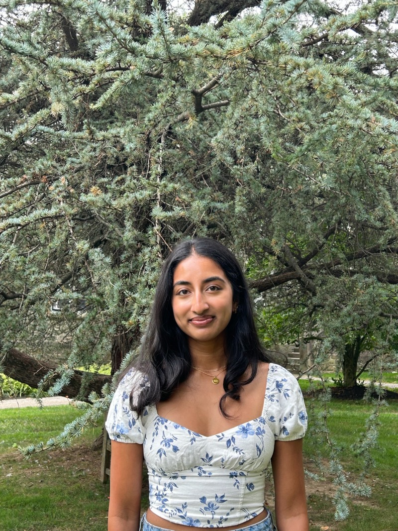 Girl smiling in front of a tree.