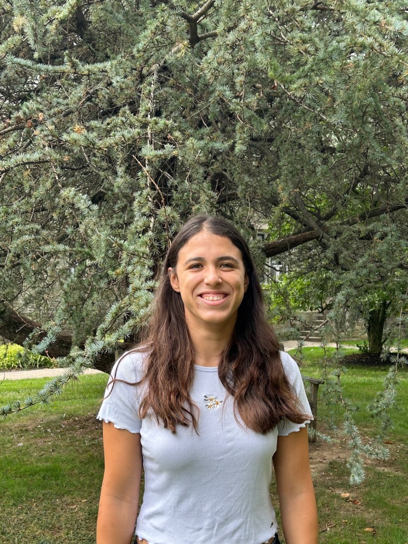 Girl smiling in front of a tree.