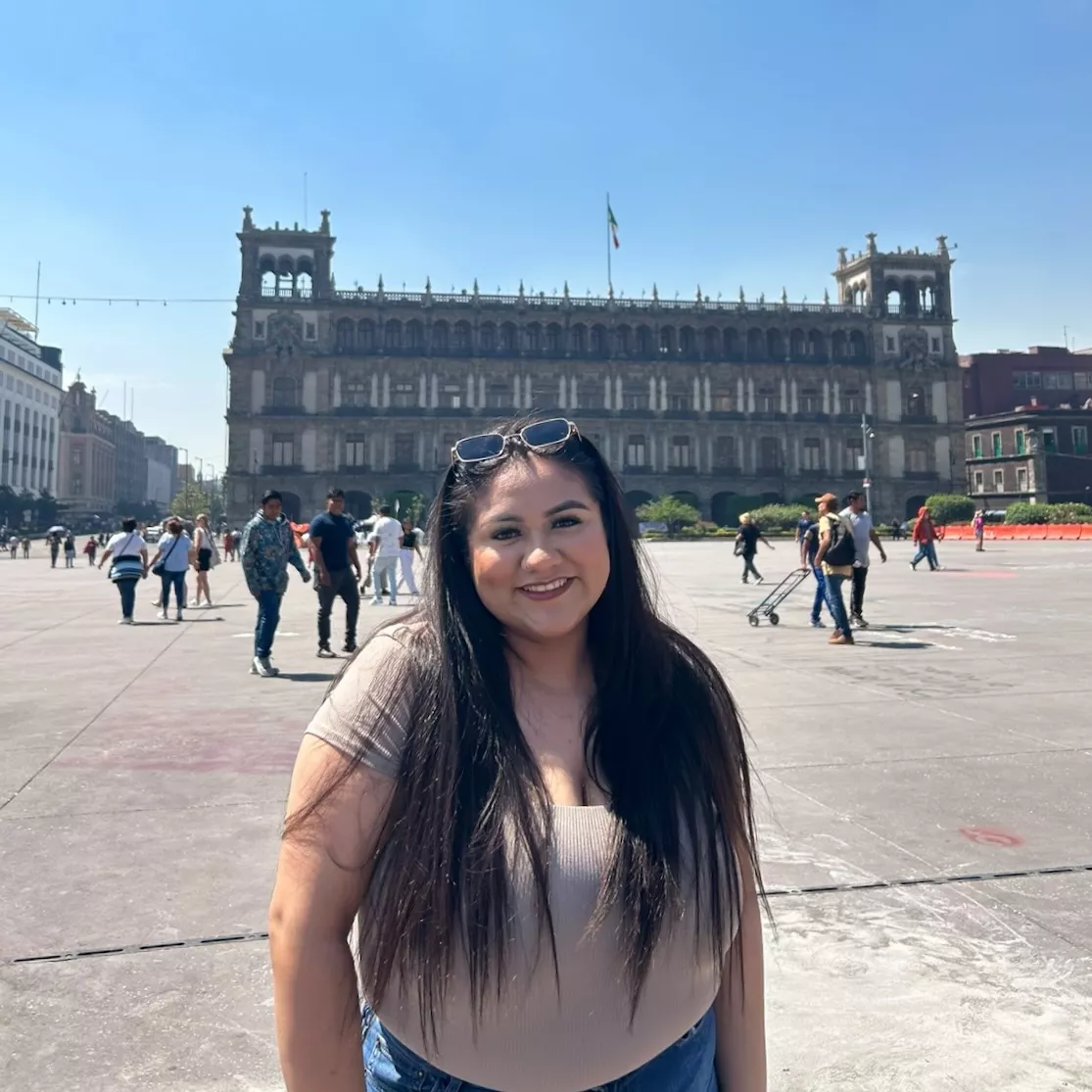 Jackie standing in a large plaza in front of a fortress-like building