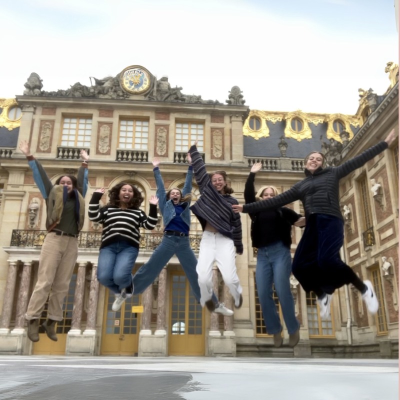 Sophie and 5 friends jumping in front of a palace courtyard