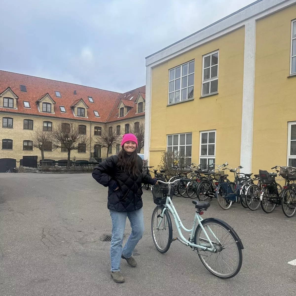 Sara standing in a courtyard next to a turquoise bike