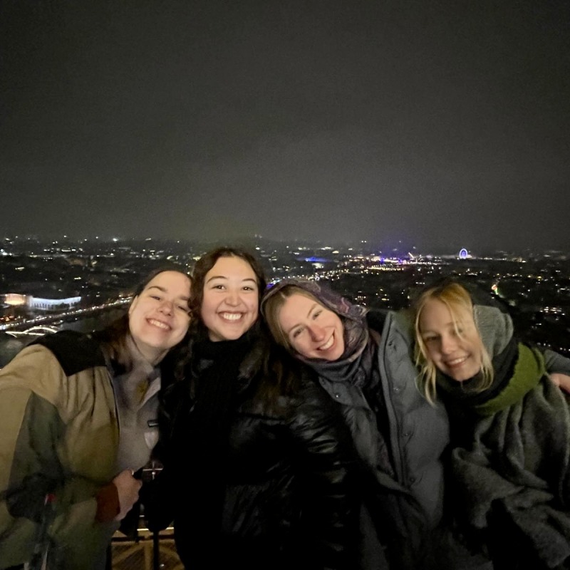 Olivia and three friends standing in front of the dark skyline of paris