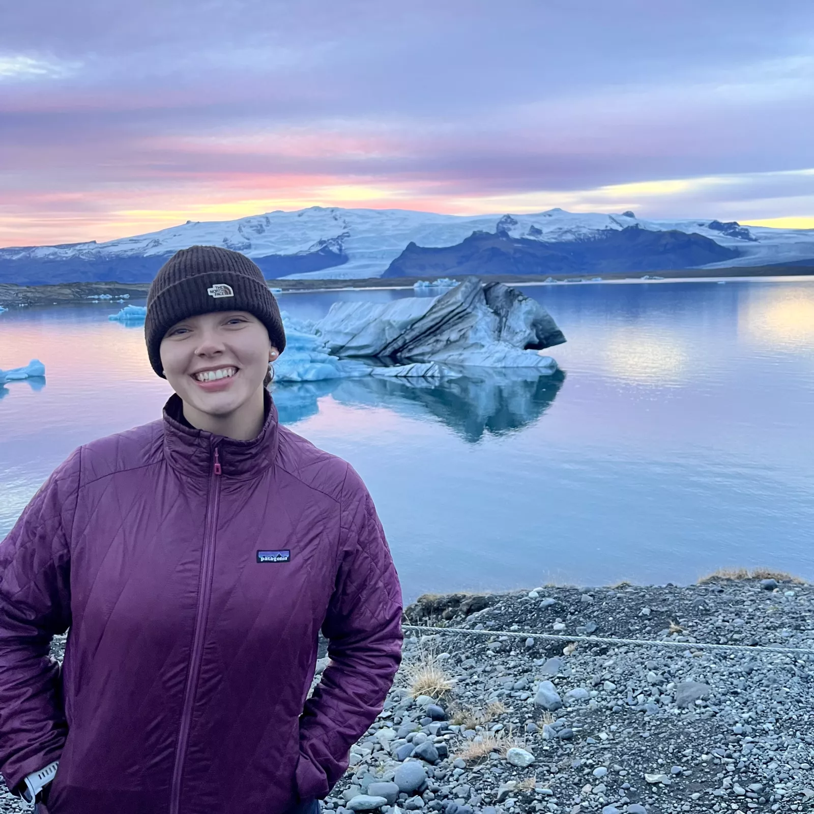 Lindsay standing in front of a glacier and beautiful purple sunset