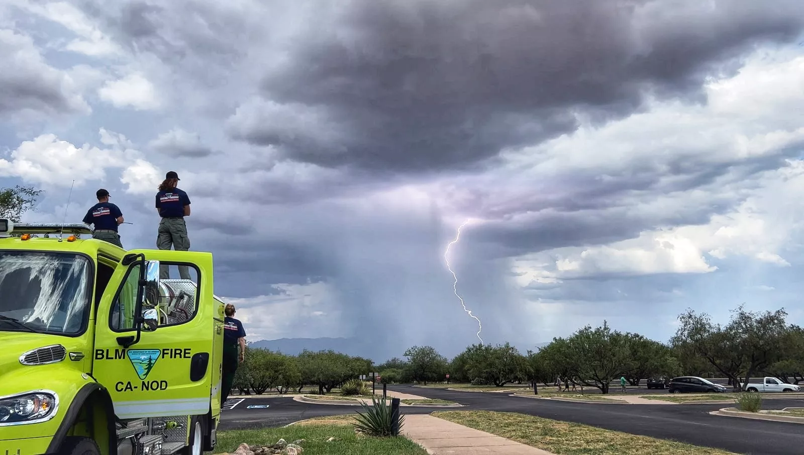 People on a truck watching storm and lightening bolt.