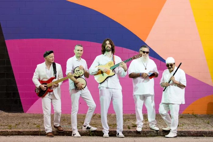 De Tierra Caliente band stands in front of colorful wall