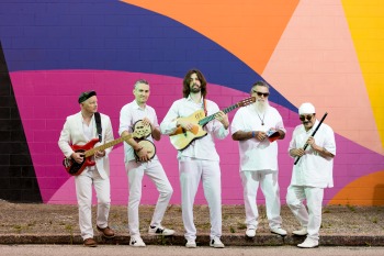 De Tierra Caliente band stands in front of colorful wall