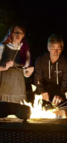 Father and daughter roasting marshmallows over a fire